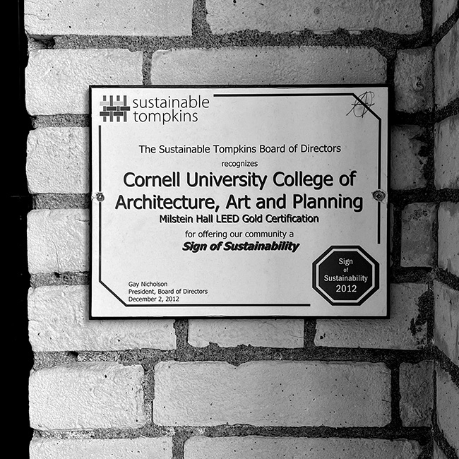 Sustainable Tompkins plaque mounted on the fire barrier wall between Milstein and Sibley Halls attesting to Milstein Hall's 'LEED Gold Certification'