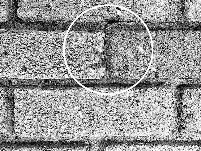 Crack in brick wall at vertical mortar joint.