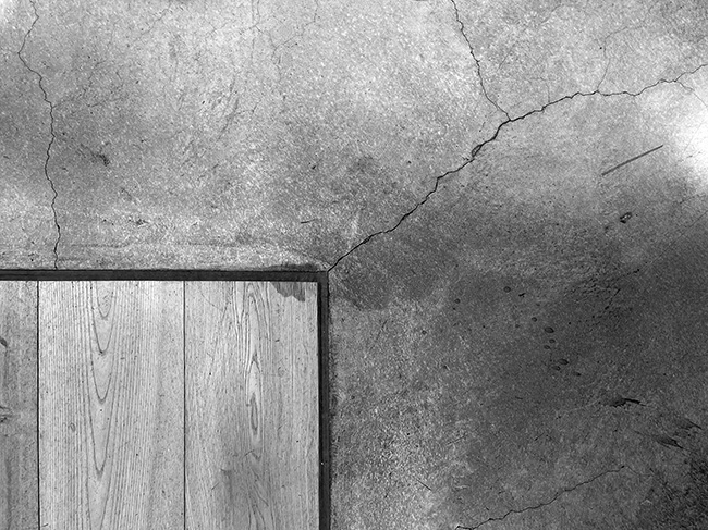 Concrete crack at corner of wood floor.