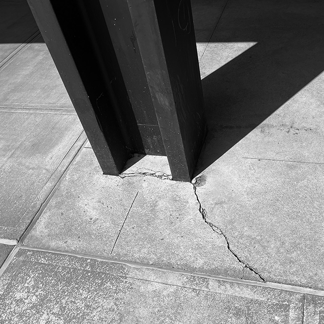 Crack in concrete pavement at corner of steel column.